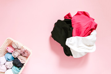 Colorful clothes vertical storage in home wardrobe. Items of clothing in textile box on soft pink background.