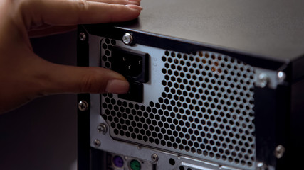 Hand switching off desktop pc button on power supply, modern computer technology