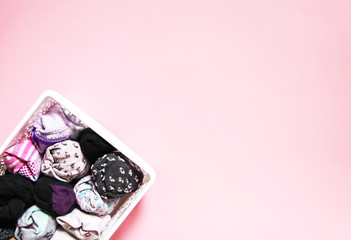 Colorful clothes vertical storage in home wardrobe. Items of clothing in a box on soft pink background.