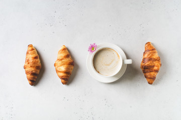 Breakfast concept with cup of coffee, croissants and flower on white background
