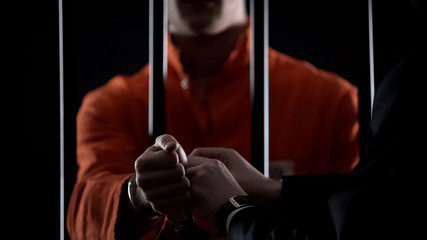 Guard taking handcuffs off criminal, releasing from jail due to good behavior