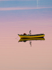 Little boat floating on the calm water under amazing sunset in Quellon, Chiloe Island in Chile