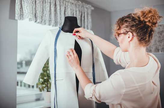 Tailor measuring lady jacket on mannequin at fashion design workshop