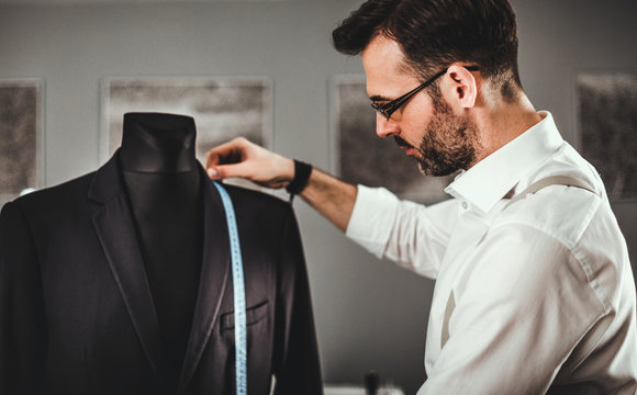 Tailor measuring jacket suit on mannequin at fashion design workshop