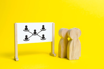 Three people are standing near the white board with the image of the hierarchy of employees in the company. Concept of business and personnel structure, analysis and optimization. Debureaucratization.