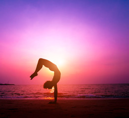 Fototapeta na wymiar Beautiful young woman practic yoga at the beach. Early morning exercise. Sunrise