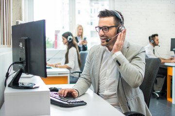 Friendly customer support agent with headset working in call center.