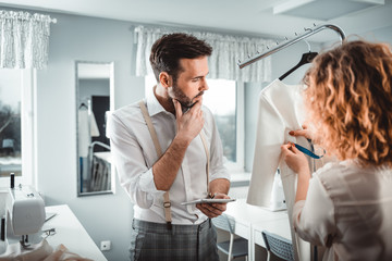 Professional tailors during work on project using digital tablet in fashion design studio