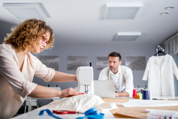 Fototapeta premium Professional tailors during work on project in fashion design studio, using sewing equipment