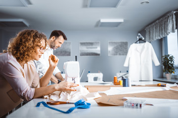 Obraz premium Professional tailors during work on project in fashion design studio, using sewing equipment