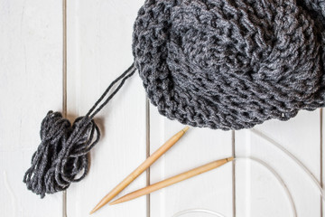 Gray knitted scarf on the white background. Wooden needles