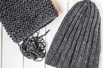 Knitted scarf and cap on the white wooden background. Knitted clothes