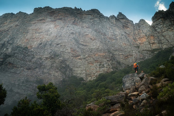 A climber hiking into a remote mountain valley with a large rock wall to climb