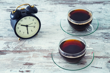 Obraz na płótnie Canvas Alarm clock and a glass of tea on the table