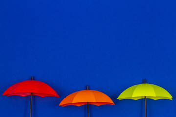 Small colorful umbrellas on blue color background