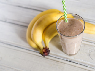 Banana smoothie or banana milkshake on wooden table