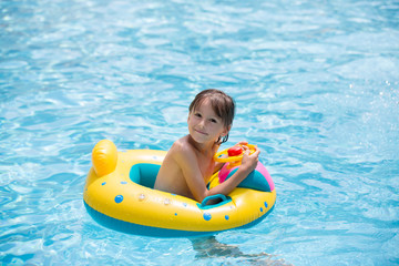 Cute child, playing with inflatable boat in pool