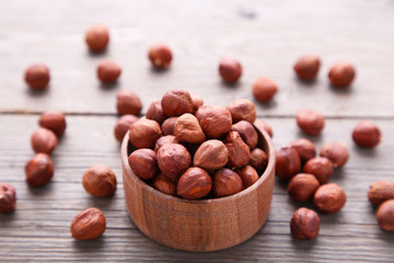 Delicious hazelnut in the wooden bowl on a grey background