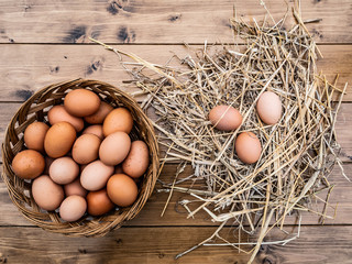 Close up top view of a basket of fresh Italian eggs with hay on the wooden table in the countryside