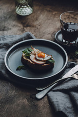 Ham and Fried Quail Egg Toast with Mustard and Basil on a dark wooden background, selective focus