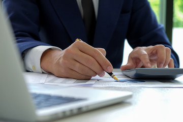 Obraz premium Businessman hand works on a calculator and uses a pen pointing at the graph.