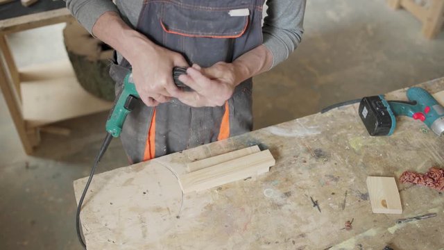 Hands on skilled carpenter placing countersink bit into portable electric drill to make holes for screws in small wooden plank