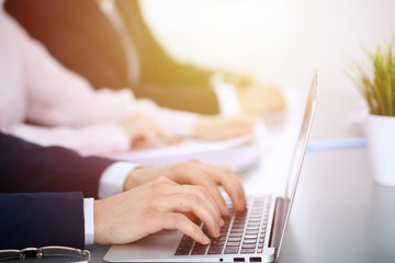 Group of business people working together in office. Man hands typing on laptop computer