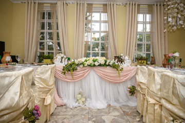 Wedding. Banquet. The chairs and round table for guests, served with cutlery, flowers and crockery and covered with a tablecloth