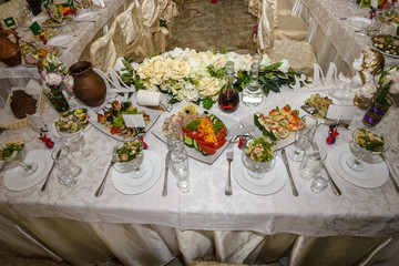 Beautiful table setting with crockery and flowers for a party, wedding reception or other festive event. Glassware and cutlery for catered event dinner