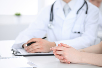 Doctor man and patient are discussing something, just hands at the table. Medicine and health care concepts