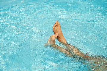 relaxing person in water. legs closeup in swimming pool