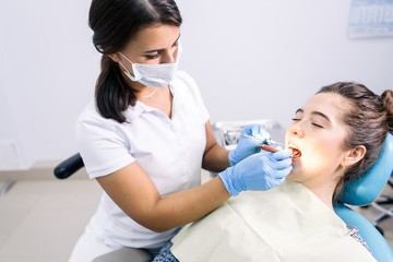 Dentist treating teeth in the clinic of a young girl