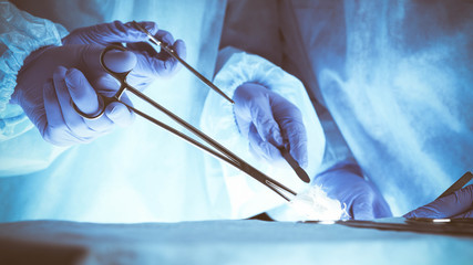 Surgeons hands holding surgical scissors and passing surgical equipment, close-up. Health care and veterinary concept
