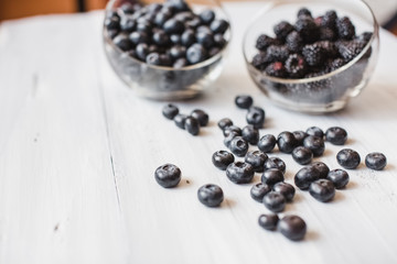 Plates with blueberry and blackberry on a wooden table top view.