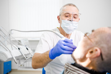 Adult experienced dentist treats teeth grandfather
