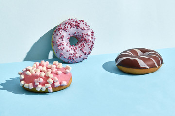 Three sweet tasty donuts in caramel and chocolate icing, on a two-color background