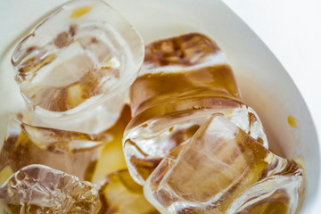 Cubes of large ice from a glass with strong coffee. Alternative Cold Brew drink. Play of color and patches of light. 