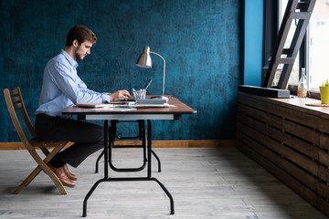 Happy young businessman using laptop at his office desk.