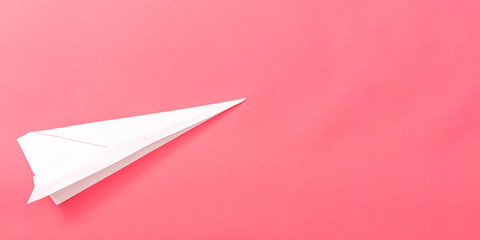 A paper plane on a pink paper background