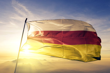 South Ossetia flag waving on the top sunrise mist fog