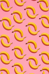 Pattern composition of a pair of bananas lying next to a pink background , top view