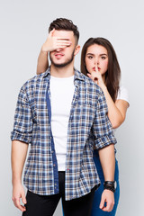Young friends couple, she closed his eyes, they are standing at white background.
