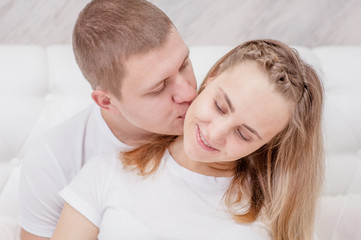 Happy woman and her husband hugging and kising on the bed