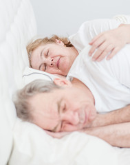 Fototapeta na wymiar elderly couple sleeping together on the bed