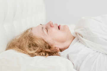 senior woman sleeping and snoring on the bed