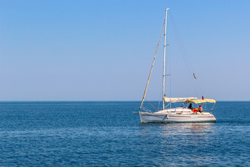 Fototapeta premium White sailing yacht with lowered sails in the sea