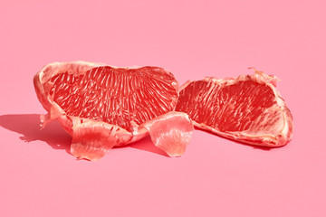 Close up high quality image of peeled slices of juicy grapefruit on a pink background