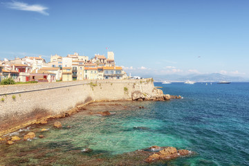 The old city wall along the coast of the French town of Antibes with the old center in the distance