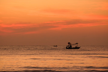 Silhouette of fisherman boat in the sea with sunrise 