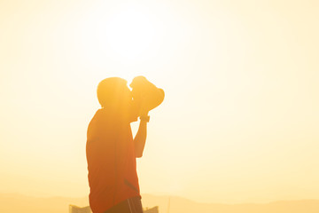 Shilloute of man taking photo during sunrise